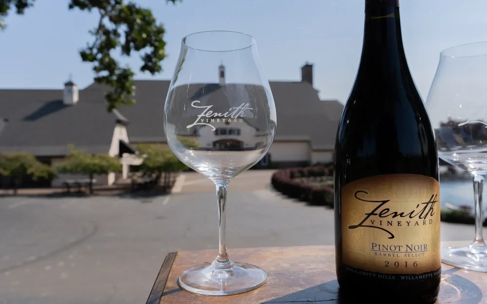 Bottle and glass of Zenith Vineyard 2016 Pinot Noir with a view of the tasting room beyond
