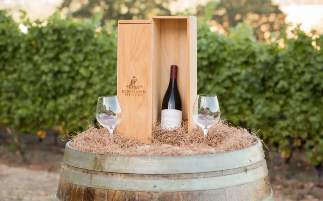 Barrel with a wooden giftbox, wine, and two glasses of Redhawk wine